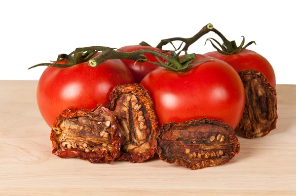 Frische und getrocknete Tomaten auf einem Holzbrett — Stockfoto
