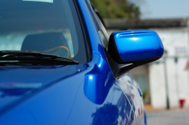 Right side mirror of shiny blue car