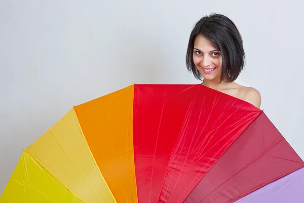 Kvinna gömmer sig över färgglada paraply — Stockfoto