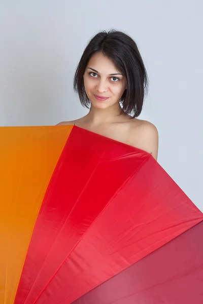 Žena skrývá přes barevný deštník — Stock fotografie