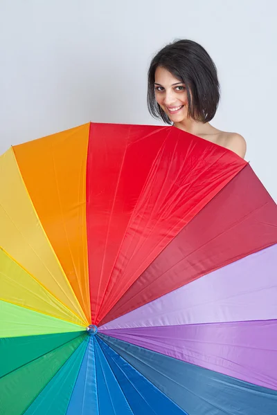 Женщина прячется за радужным зонтиком — стоковое фото