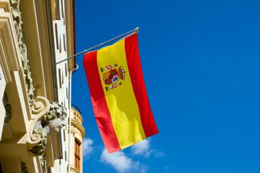 Spanish flag flying at an old building clipart