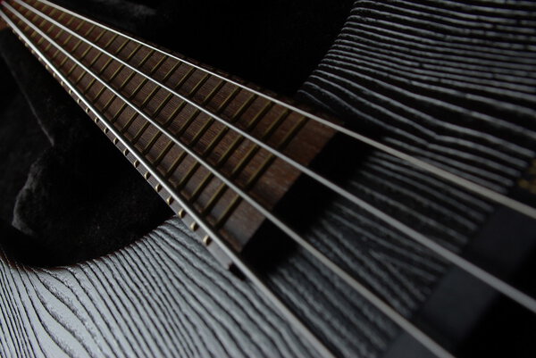 Bass guitar neck on the black background