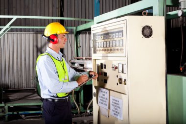 Industrial technician writing down machine setting figures clipart