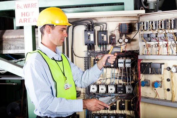 Eletricista verificando a temperatura da caixa de controle da máquina — Fotografia de Stock