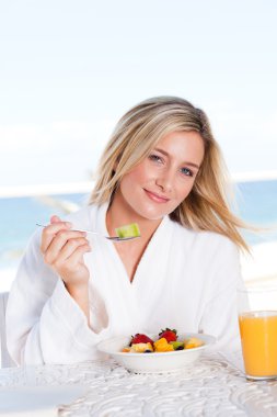 Young woman eating breakfast clipart