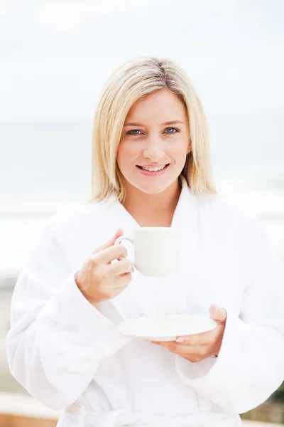 Молодая женщина пьет кофе в халате — стоковое фото