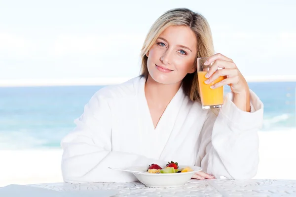 Jonge vrouw drinken sinaasappelsap bij ontbijttafel — Stockfoto