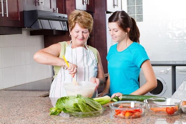 Barnbarn tittar mormor matlagning i köket — Stockfoto