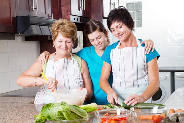 Teen girl watching mother and grandmother cooking — Stock Photo, Image