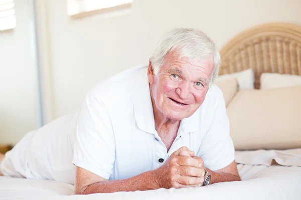 Starší muž ležící na posteli — Stock fotografie