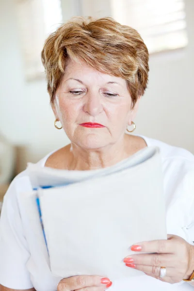 Äldre kvinna läsa tidningen — Stockfoto