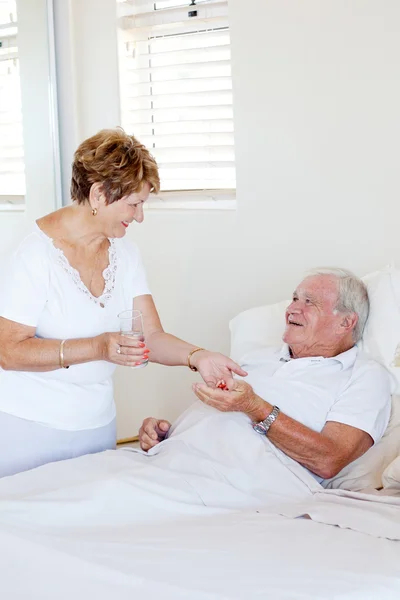 Заботливая старшая жена дает лекарства мужу — стоковое фото