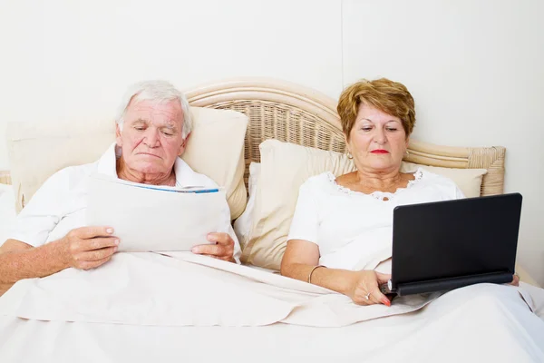 Seniorpaar liest im Bett — Stockfoto
