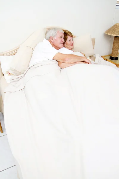 Пожилая пара, обнимающаяся в постели — стоковое фото