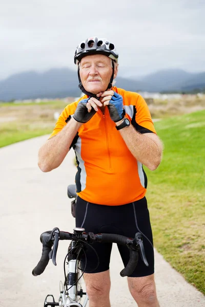 Hombre mayor que se pone su casco de ciclismo — Foto de Stock