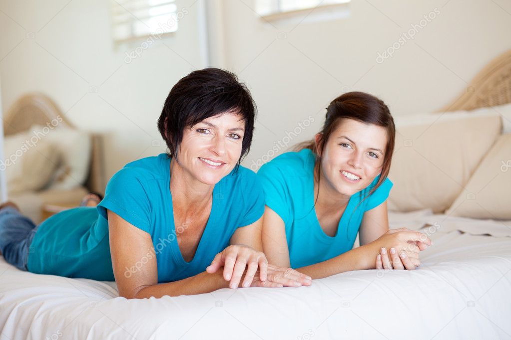 Mother and daughter lying on bed