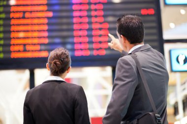 Businessman and businesswoman checking flight information clipart