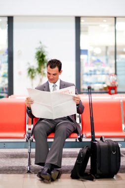 Businessman reading newspaper at airport clipart