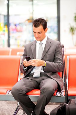 Businessman sending text messages at airport clipart