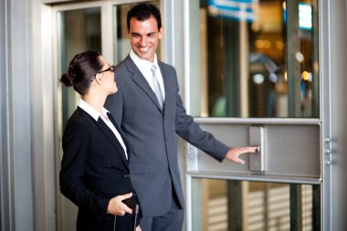 Businessman and businesswoman using elevator at airport clipart