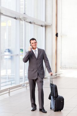 Businessman talking on mobile phone at airport clipart