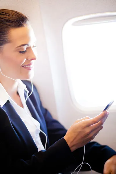 Zakenvrouw luisteren muziek op vliegtuig — Stockfoto