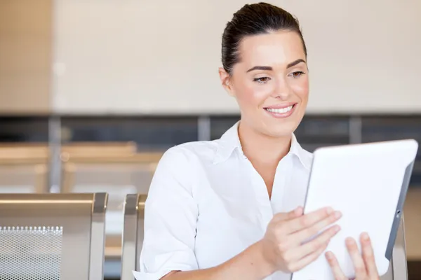 Güzel bir genç kadın havaalanında tablet bilgisayar kullanarak — Stok fotoğraf