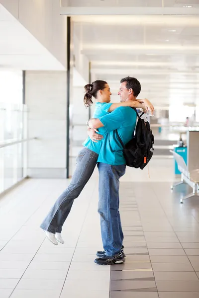 Happy young couple hugging at airport — Stock Photo, Image