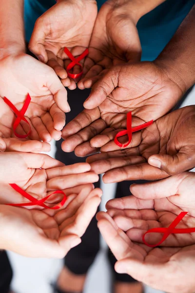 Grupo de multirracial segurando fita vermelha com ambas as mãos — Fotografia de Stock