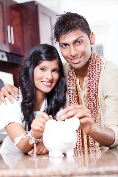 Indian couple put coin in piggybank