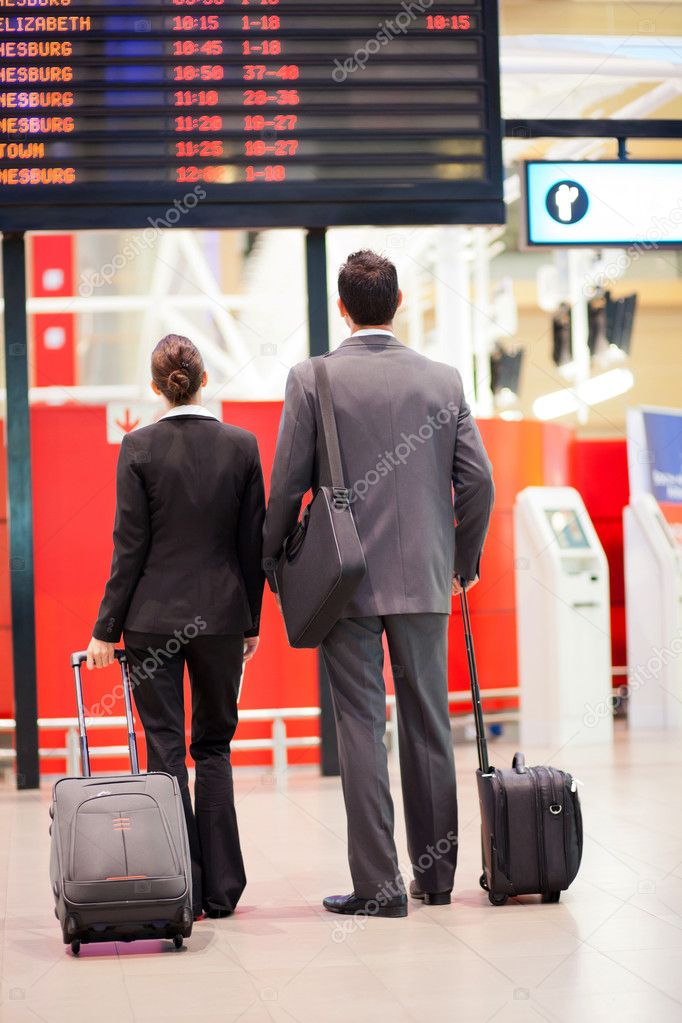 Business travellers looking at airport information board