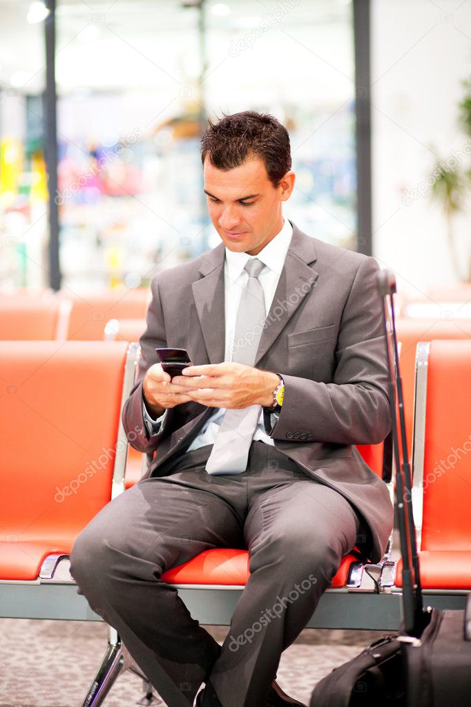 Businessman sending text messages at airport