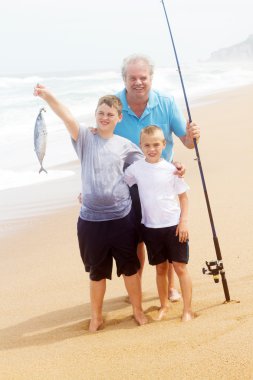 Grandpa and grandsons catching fish on beach clipart