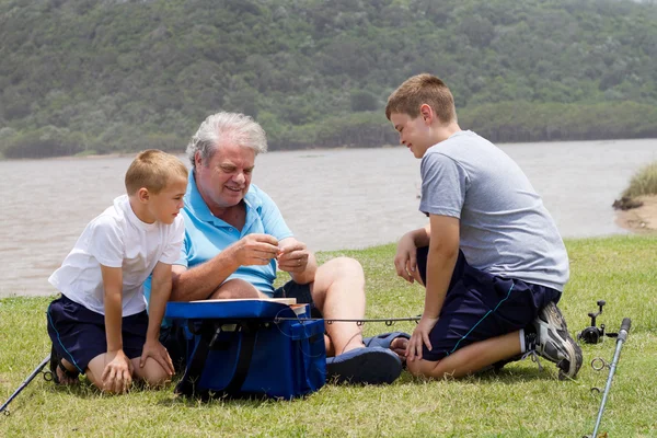 Дедушка и внуки рыбачат на озере — стоковое фото