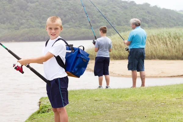 Счастливый маленький мальчик рыбачит у озера — стоковое фото