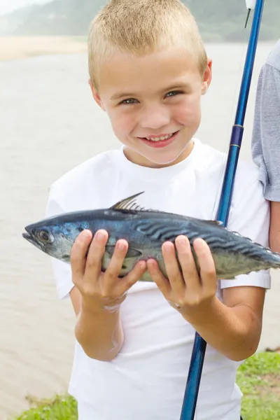 Menino mostrando um peixe que ele pegou — Fotografia de Stock