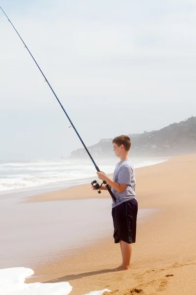 Teenage boy fishing on beach — Stock Photo, Image