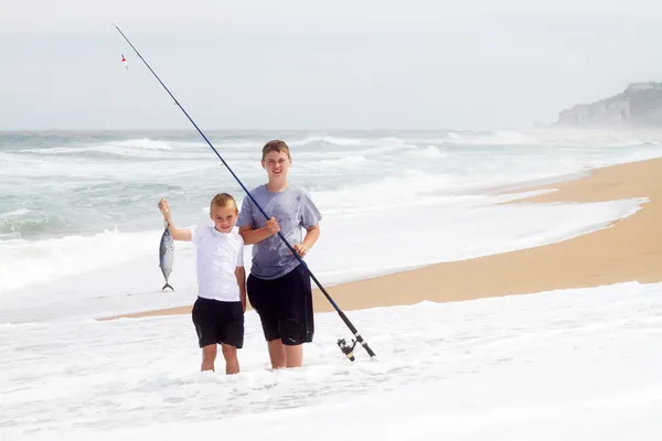 Two boys catching fish on beach — Stock Photo, Image