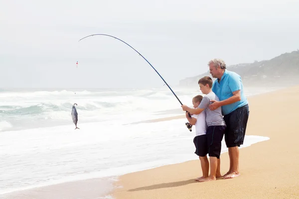 Grandpa and grandsons pulling fish out of water — Stock Photo, Image