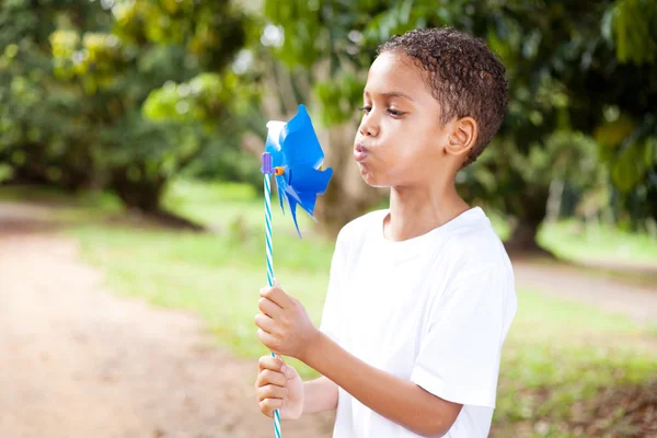 Little boy blowing on a pinwheel — Stock Photo, Image