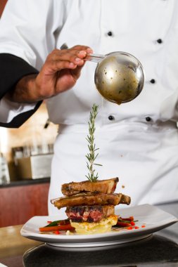 Chef adding sauce to meat dish clipart