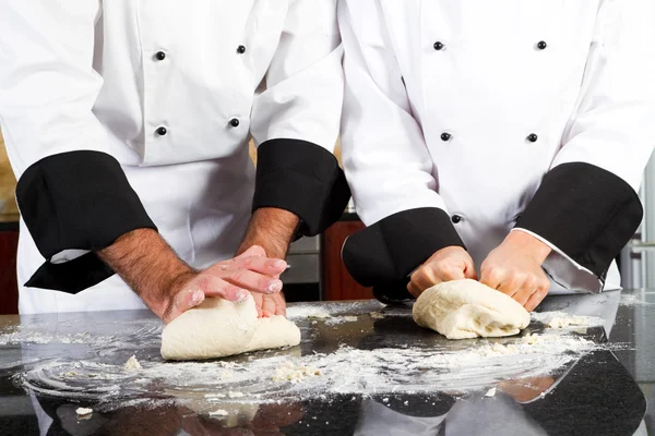 Mains de chef professionnel pétrissant pâte à pain sur comptoir de cuisine — Photo
