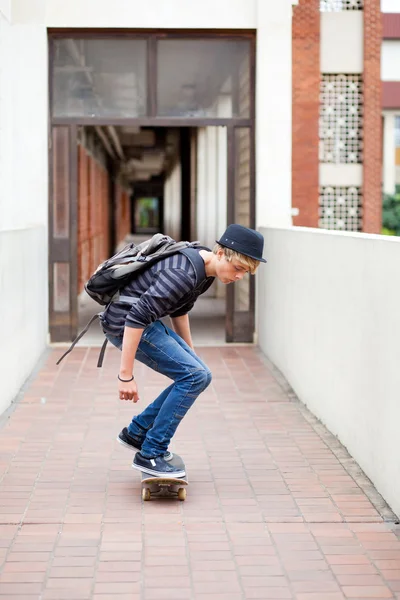 Хлопчик-підліток скейтбординг у шкільному проході — стокове фото