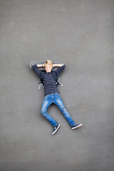 Tonåring skateboardåkare liggande på skateboard — Stockfoto