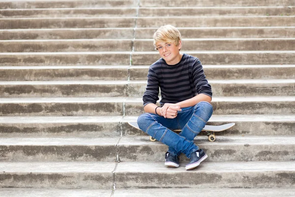 Adolescent garçon assis sur skateboard — Photo