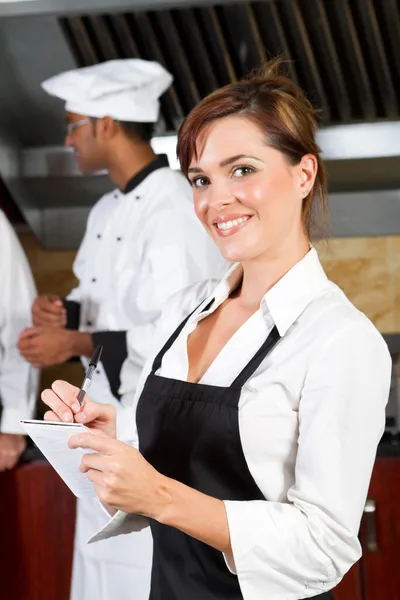 Fiatal, boldog pincérnő az étterem konyha Stock Kép