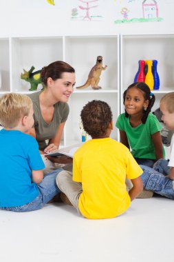 Teacher reading book to preschool students clipart