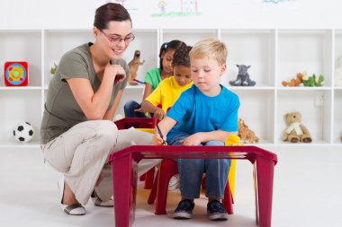 Preschool students and female teacher in kindergarten clipart