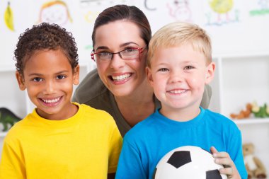 Happy preschool teacher and two boys in classroom clipart